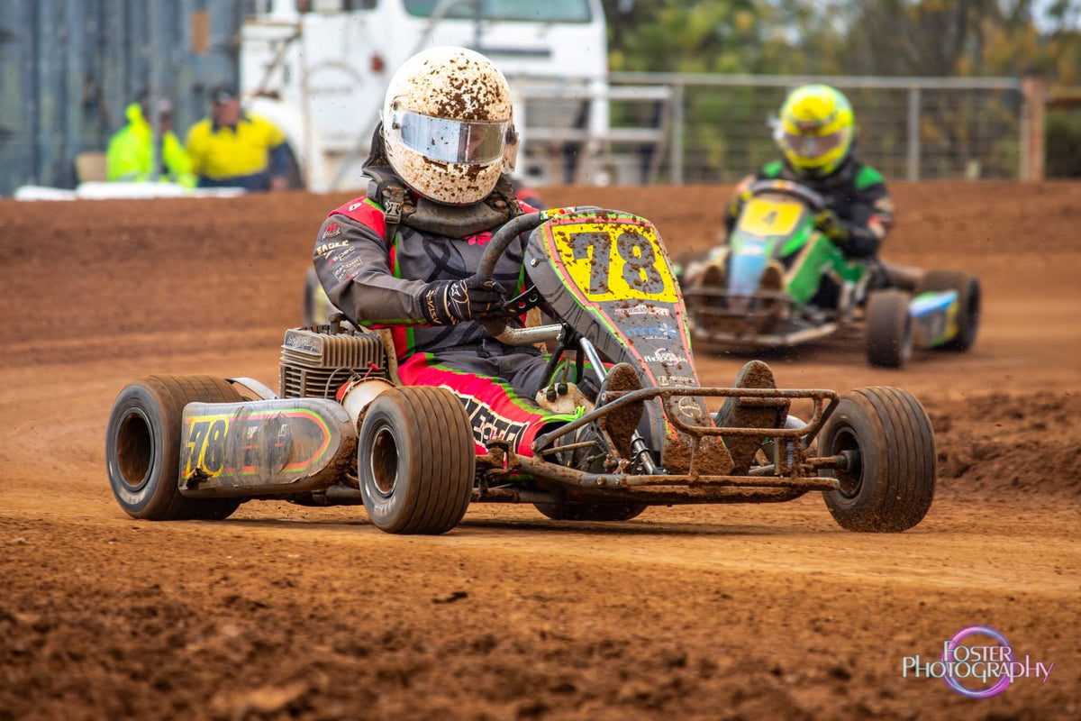 Omega kart number 183 racing on dirt, with green and purple bodywork